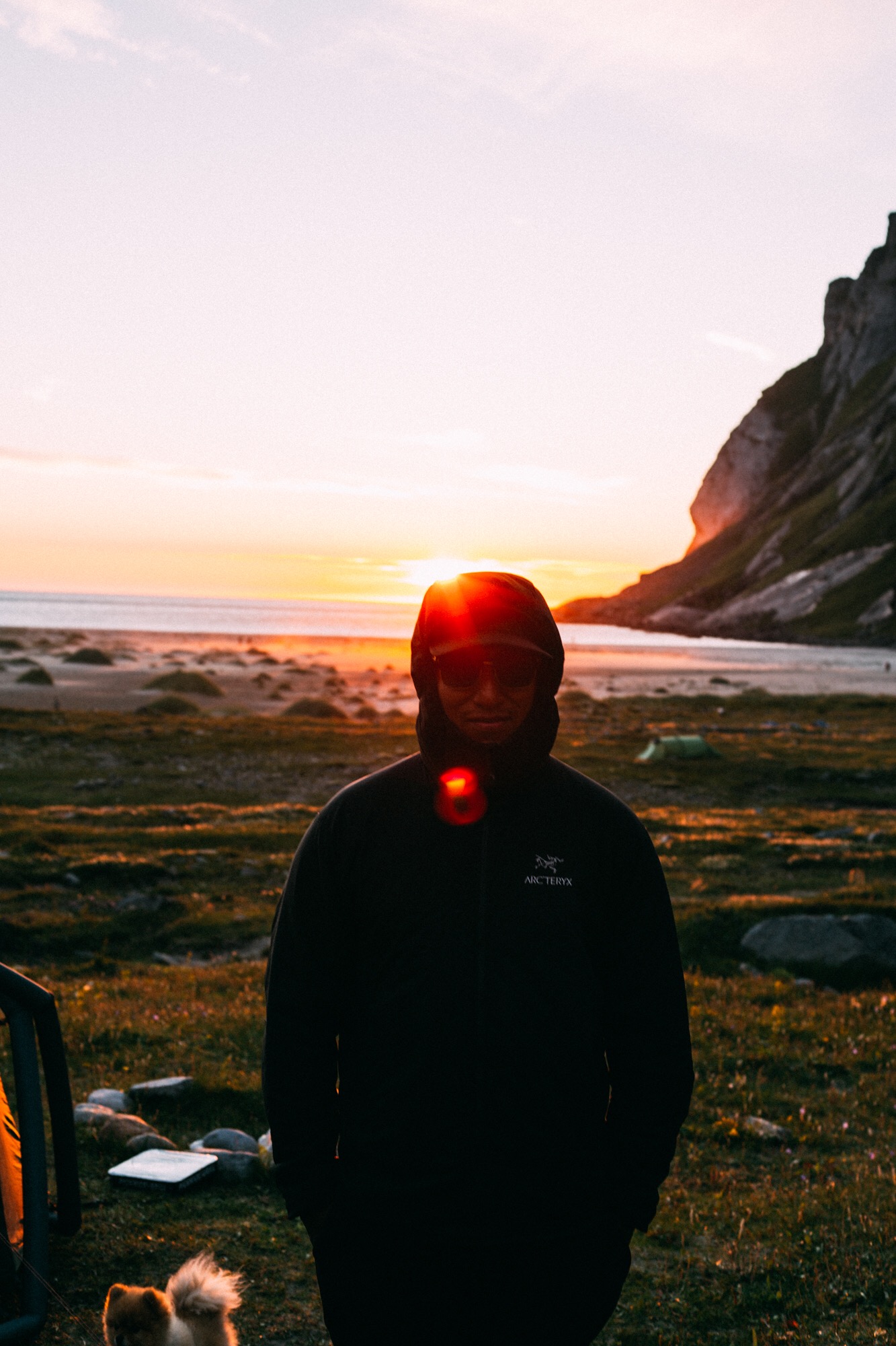 Rune on a beach at sunset, with the sea and a steep mountain behind.